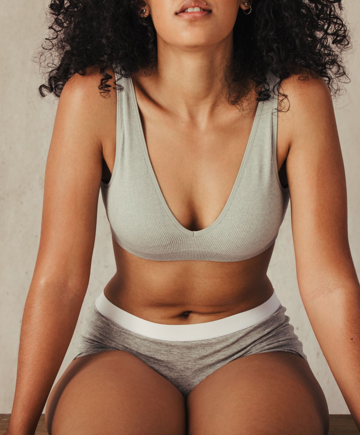 Model in casual gray intimate wear, seated.