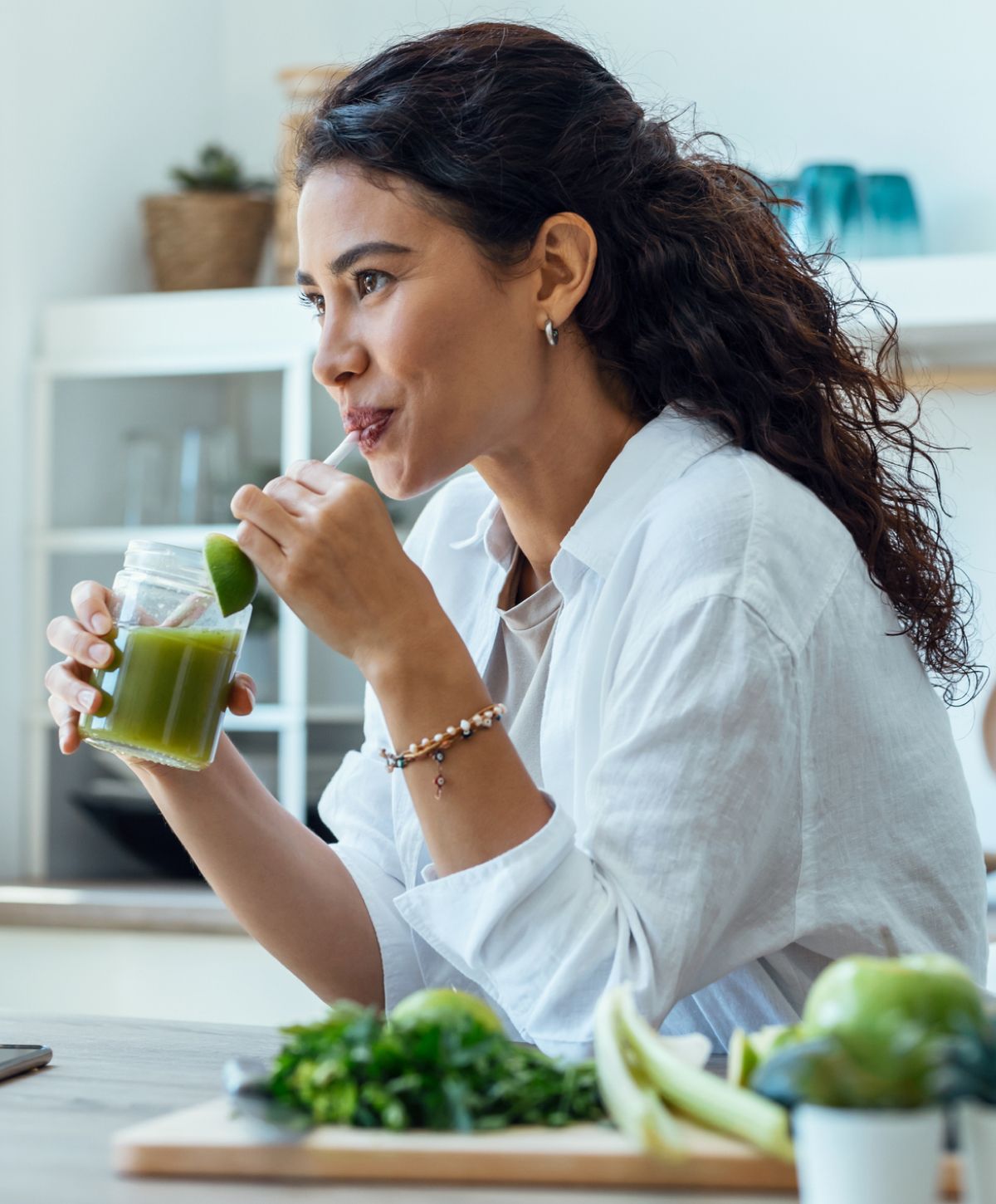 Woman enjoying a healthy green drink at home.