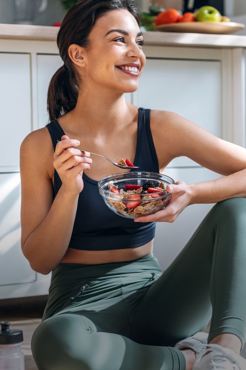 Smiling woman eating healthy breakfast at home.