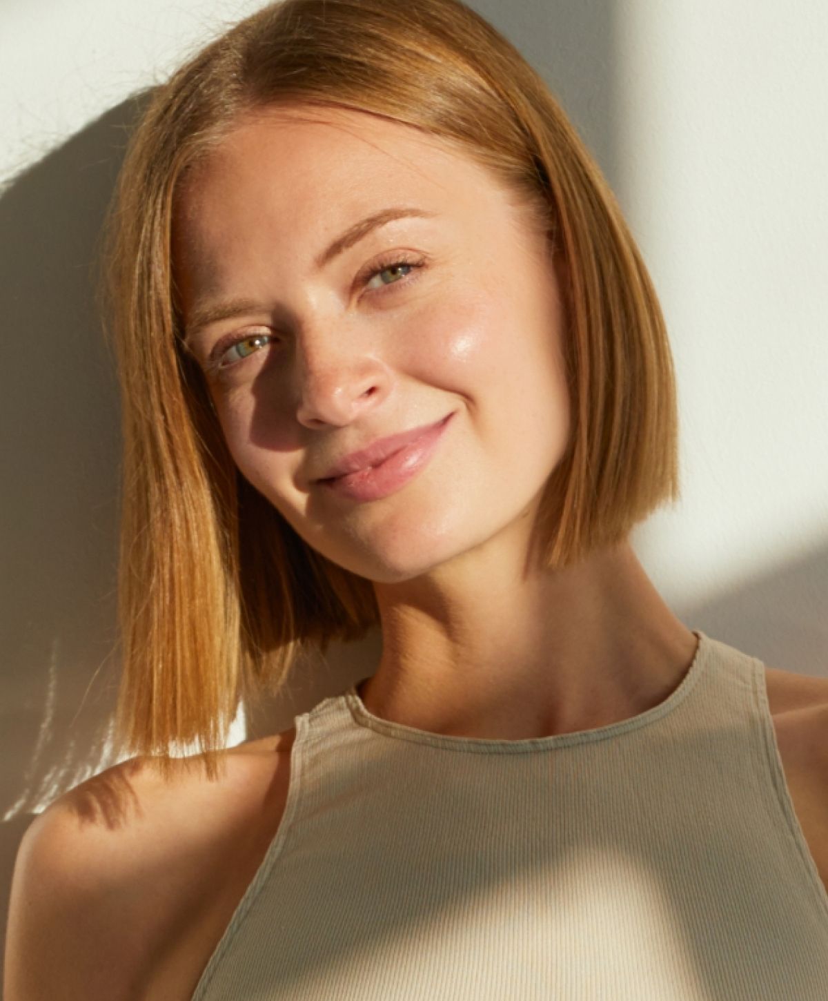 Smiling woman with short hair in sunlight.