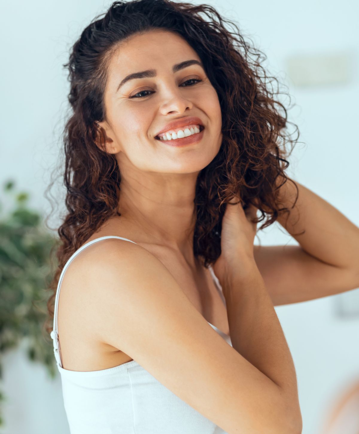Smiling woman with curly hair in bright setting.