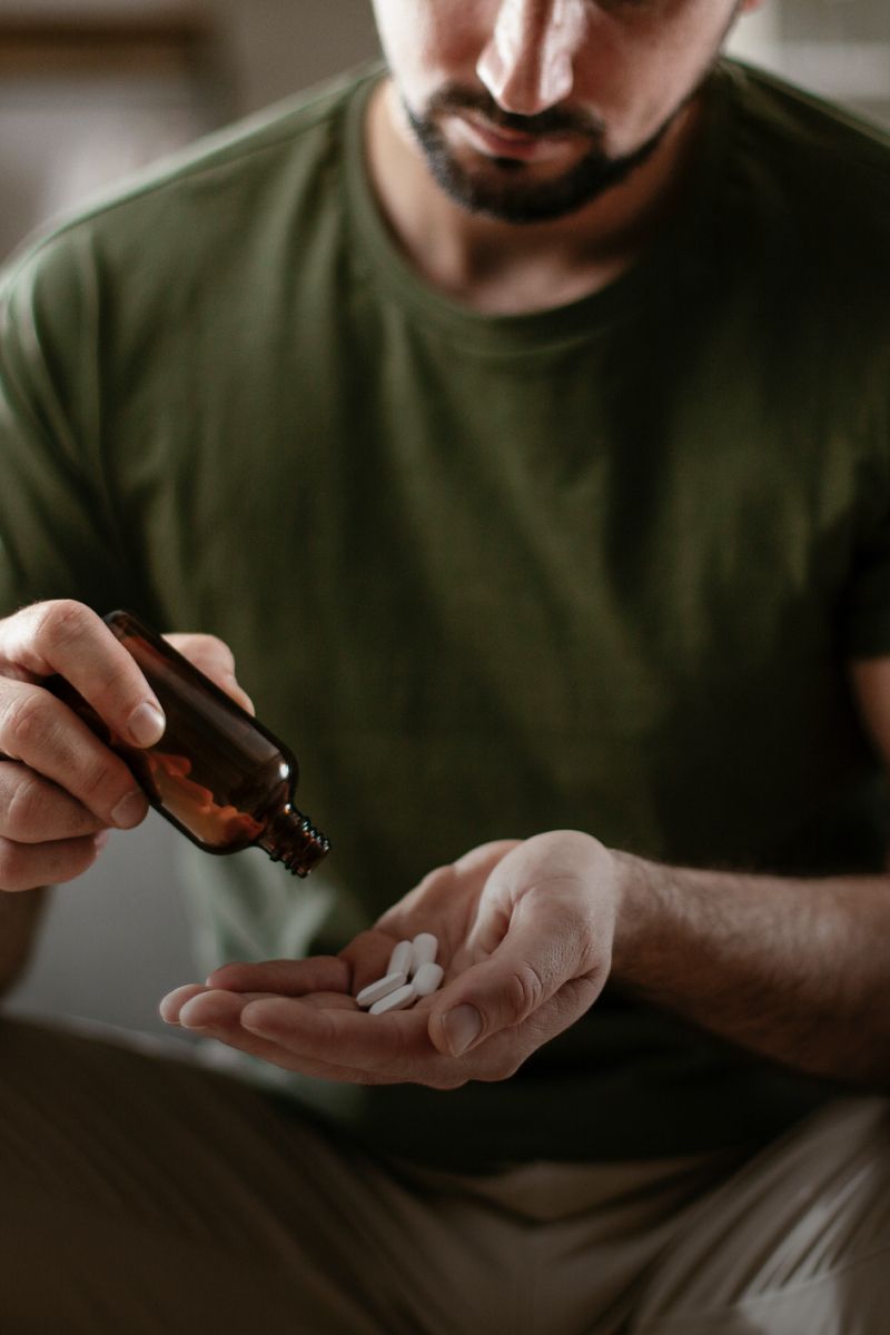 Man pouring pills into palm from bottle.