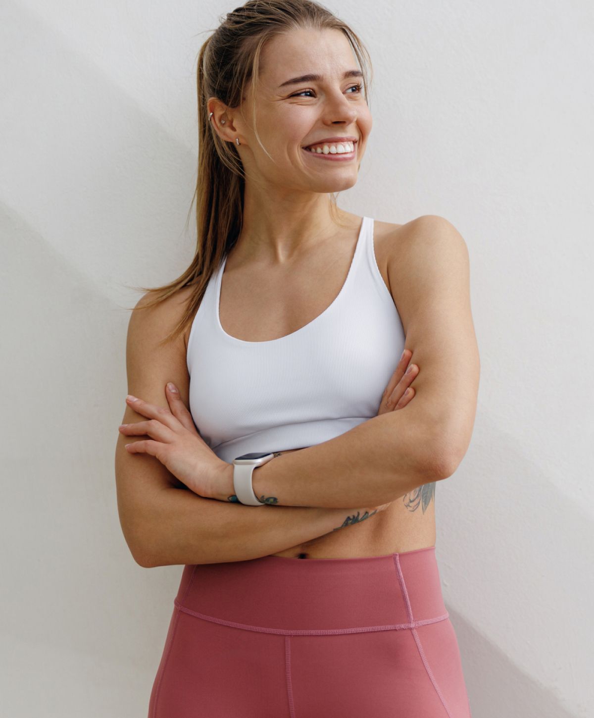 Smiling woman in athletic wear, arms crossed.