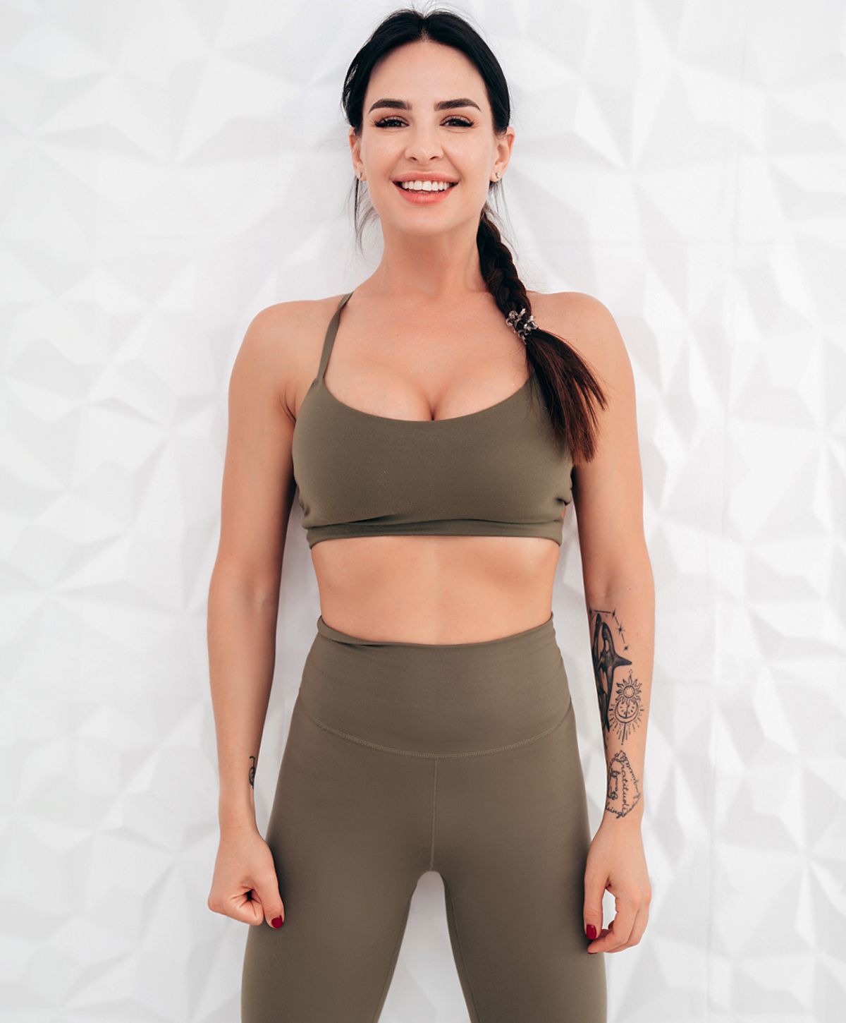 Smiling woman in athletic wear against patterned background.