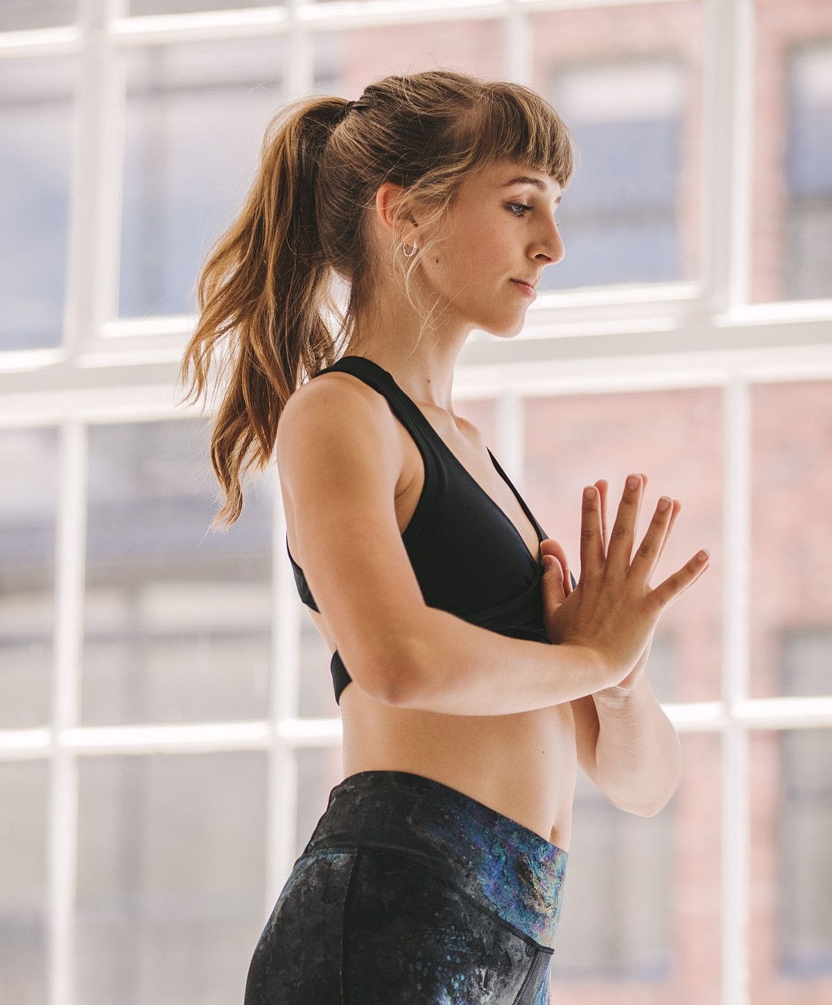 Woman practicing yoga indoors by a window.