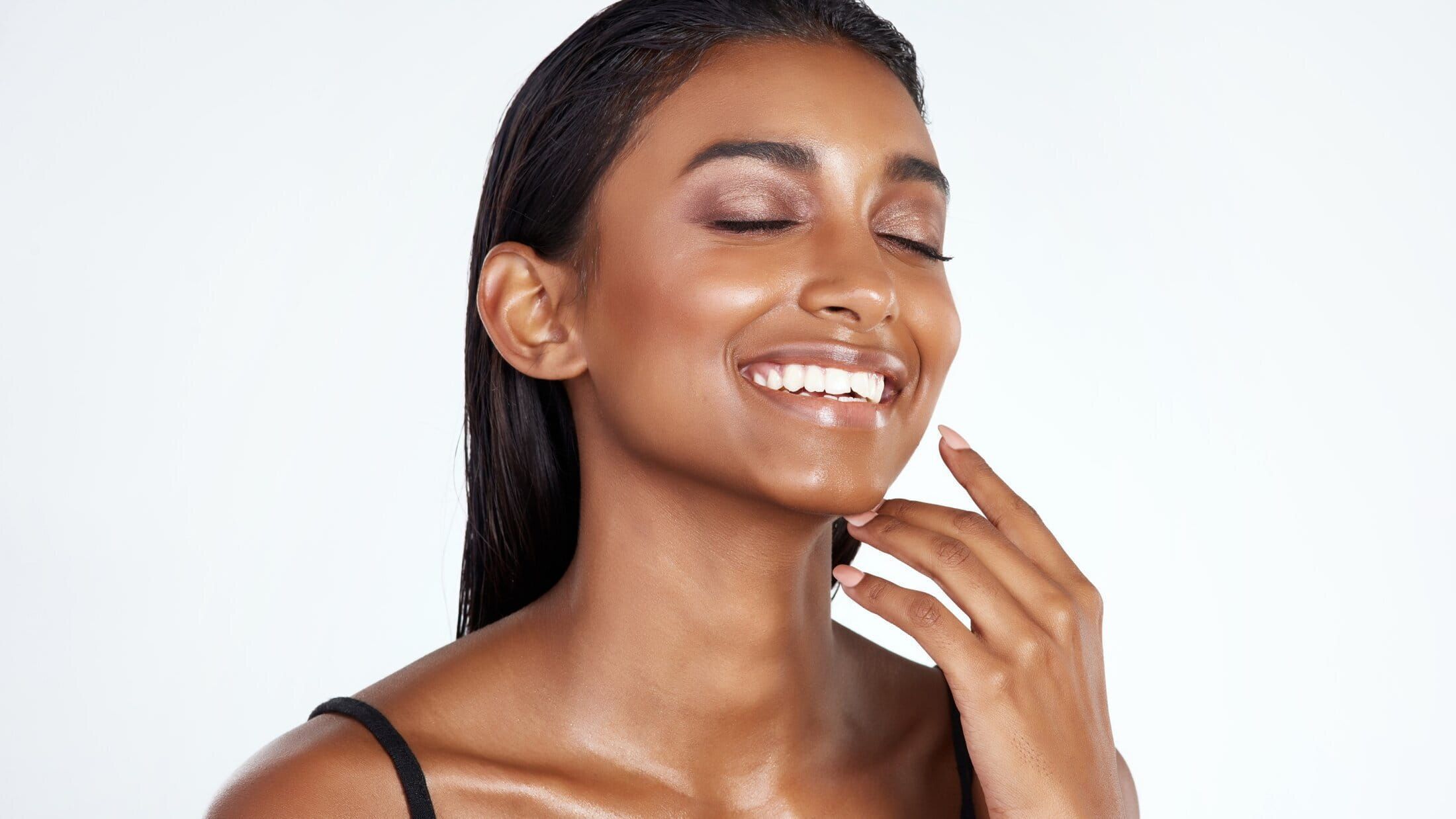 Smiling woman with glowing skin and natural makeup.