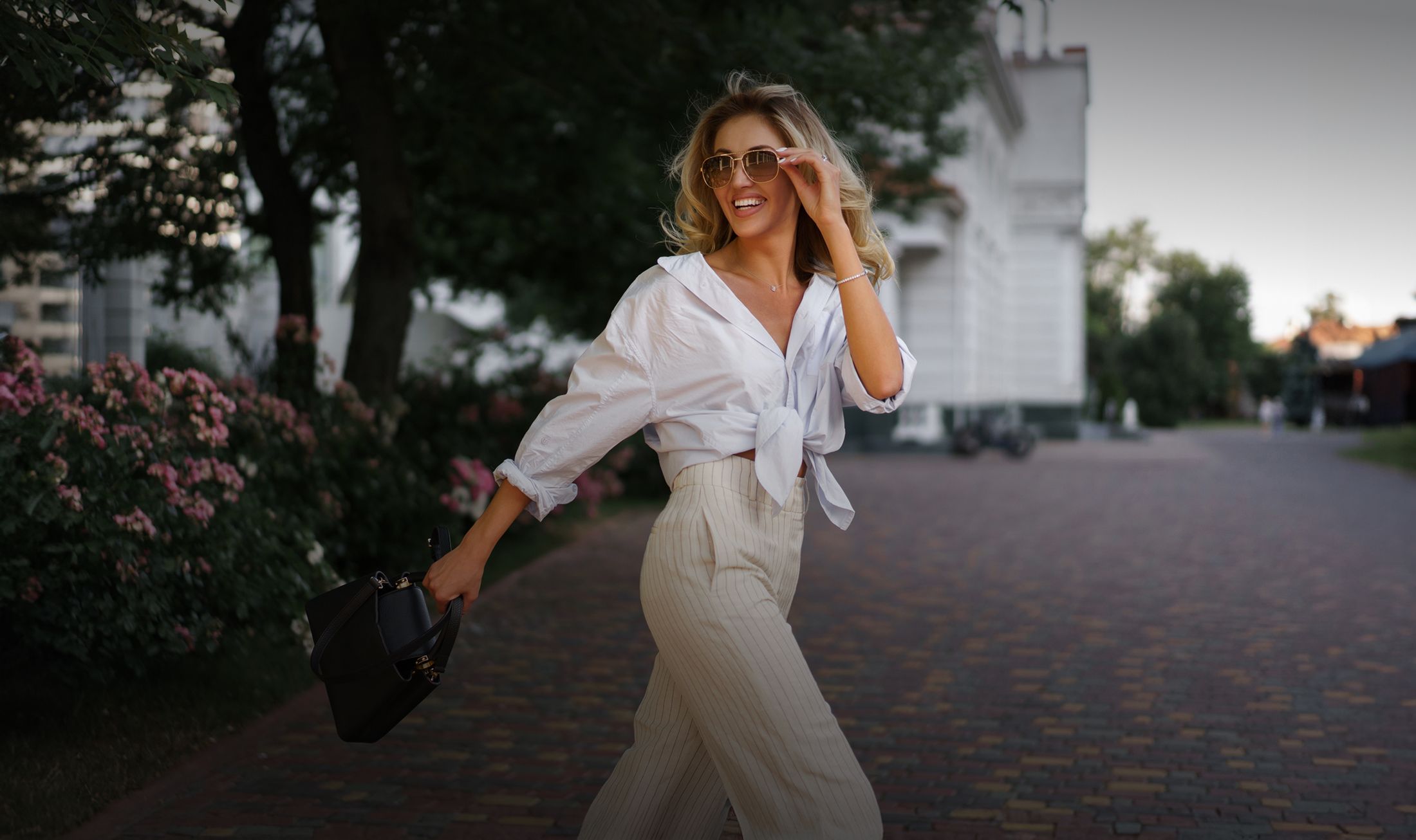 Woman in stylish outfit walking outdoors happily.