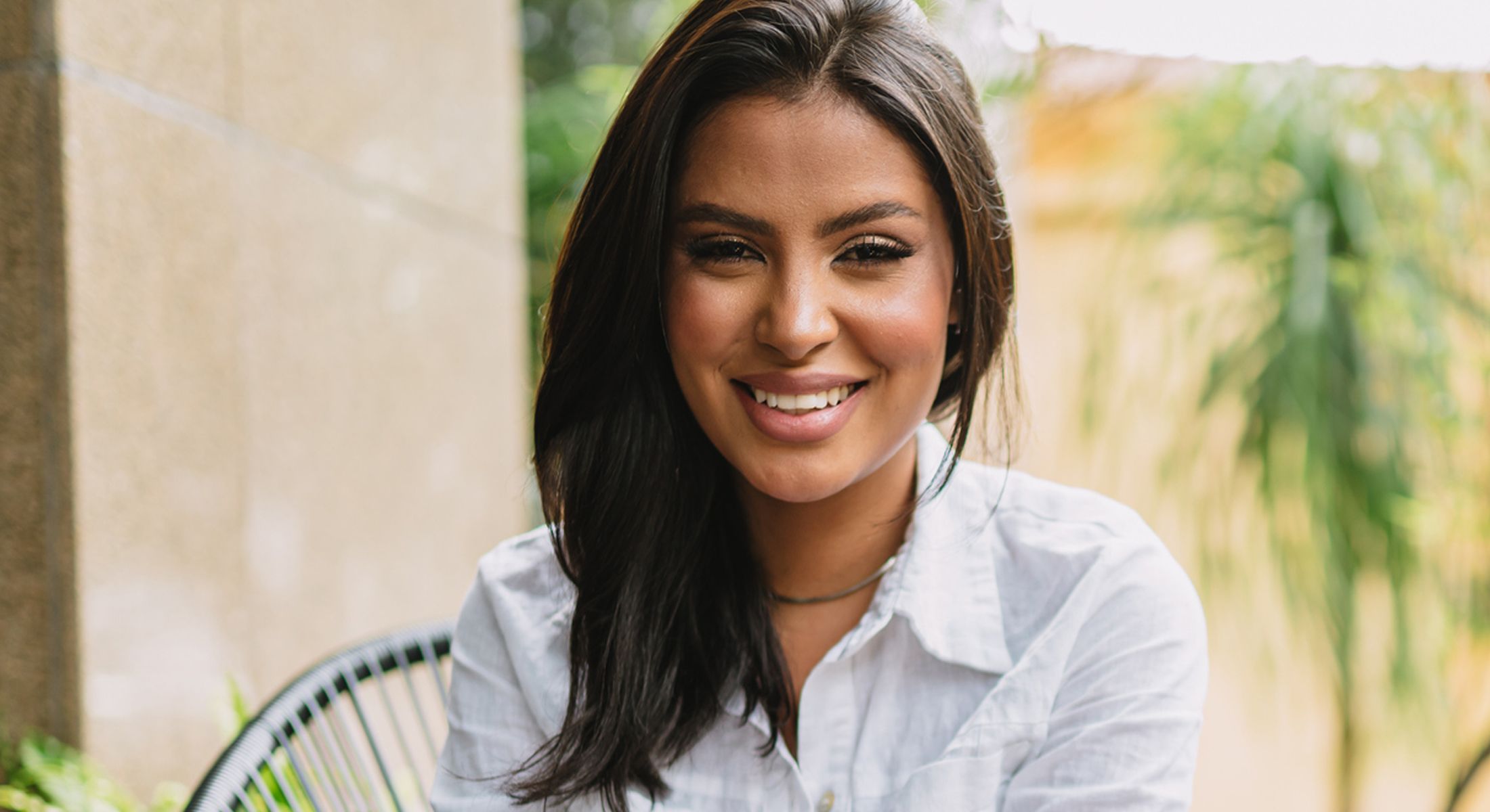 Smiling woman outdoors in casual white shirt.