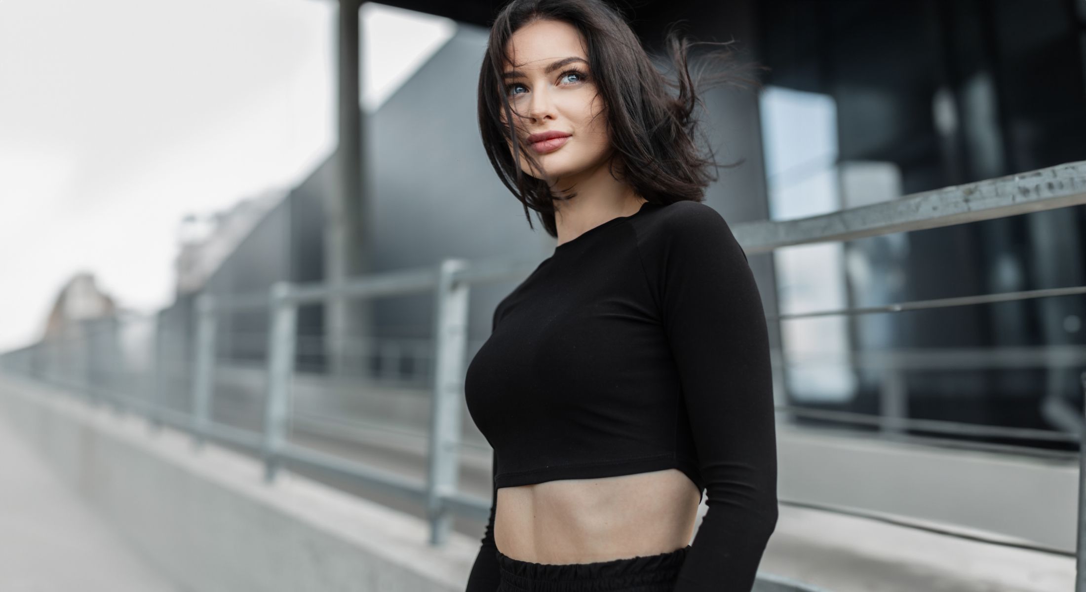 Woman in black top against urban background.